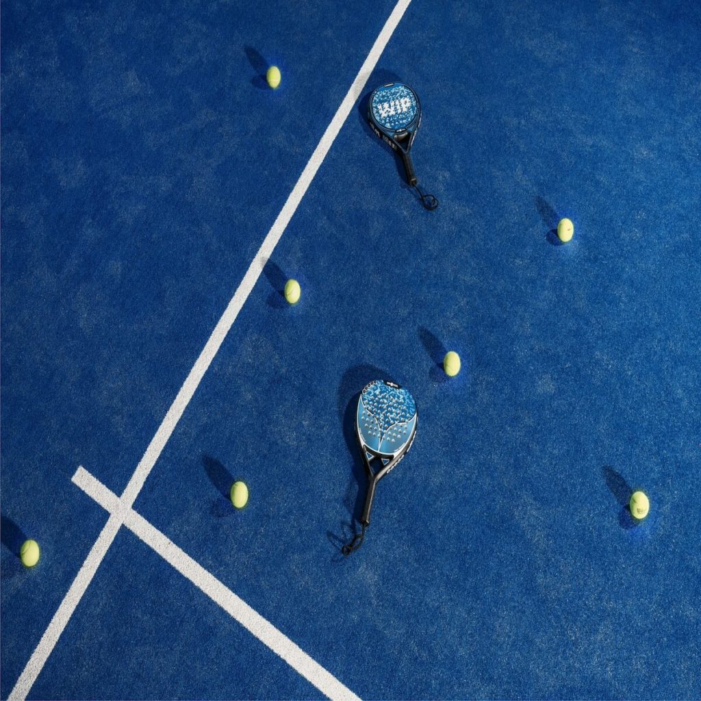 Immagine di un campo da Padel con delle racchette e delle palline per terra